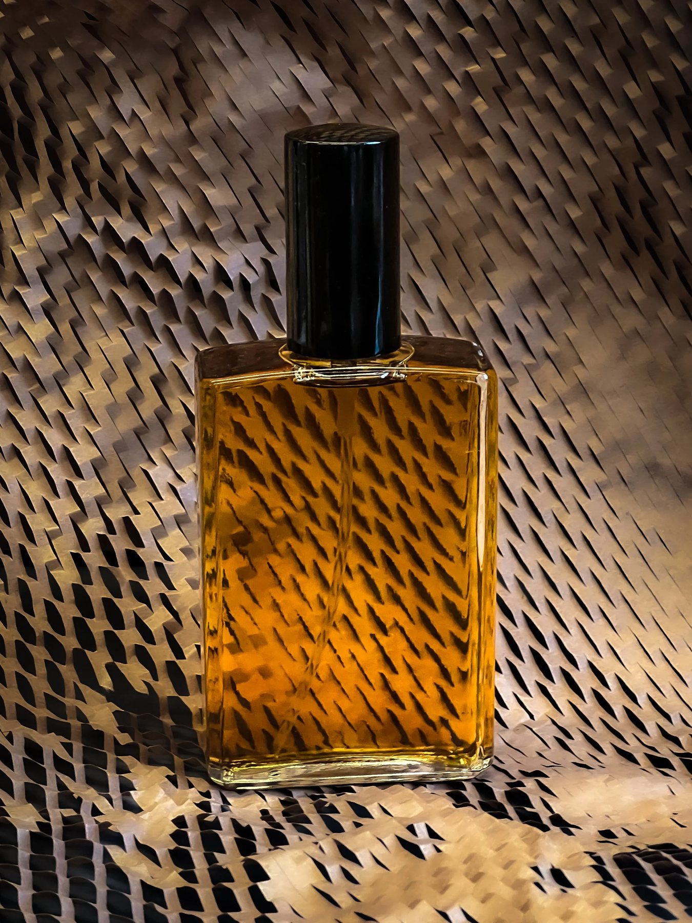 A rectangular bottle of amber /forest bath fragrance against a dark textured background.