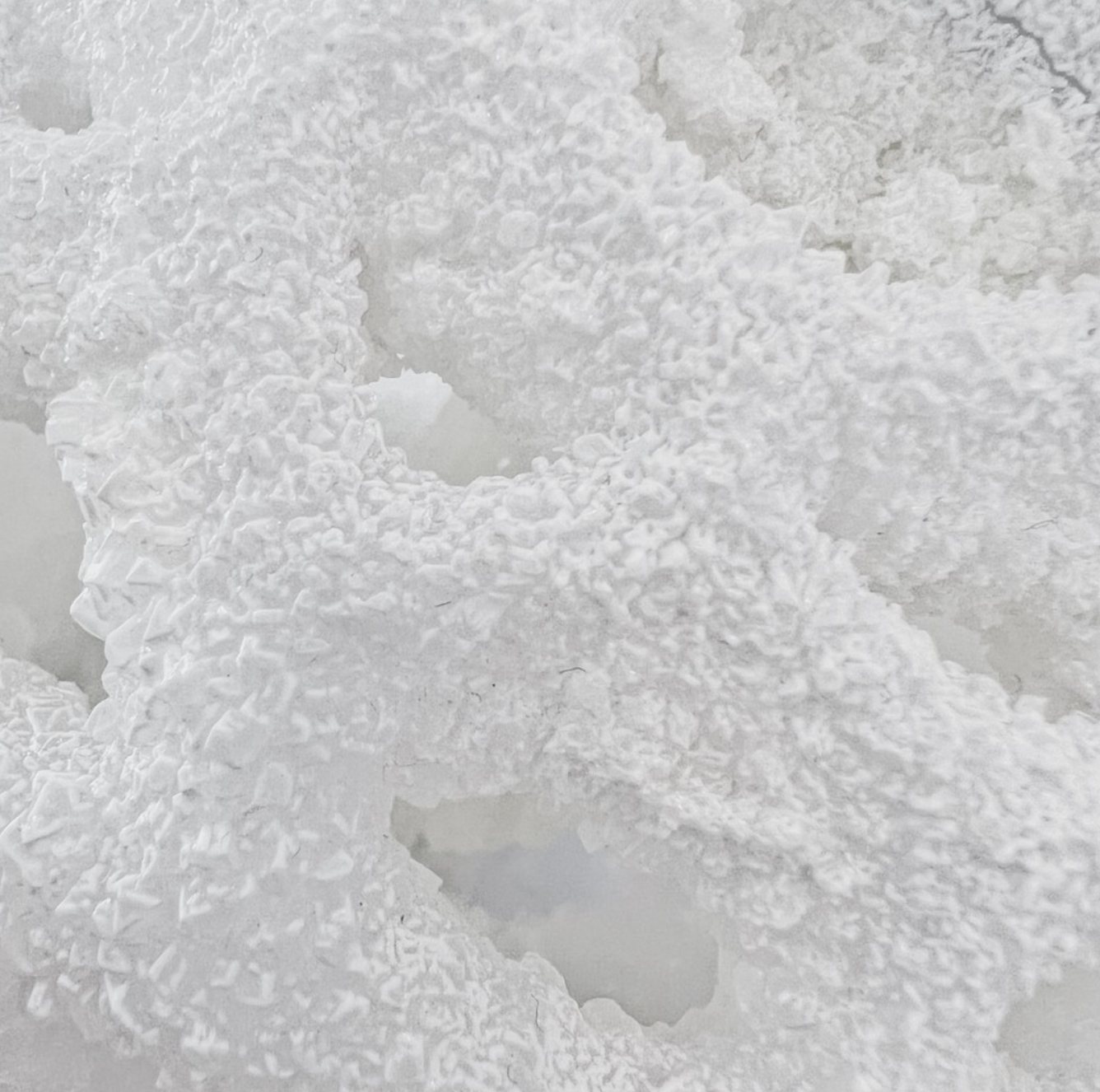 Close-up of the white crystal surface of the bottle, dense and frost-like, over the resin form.