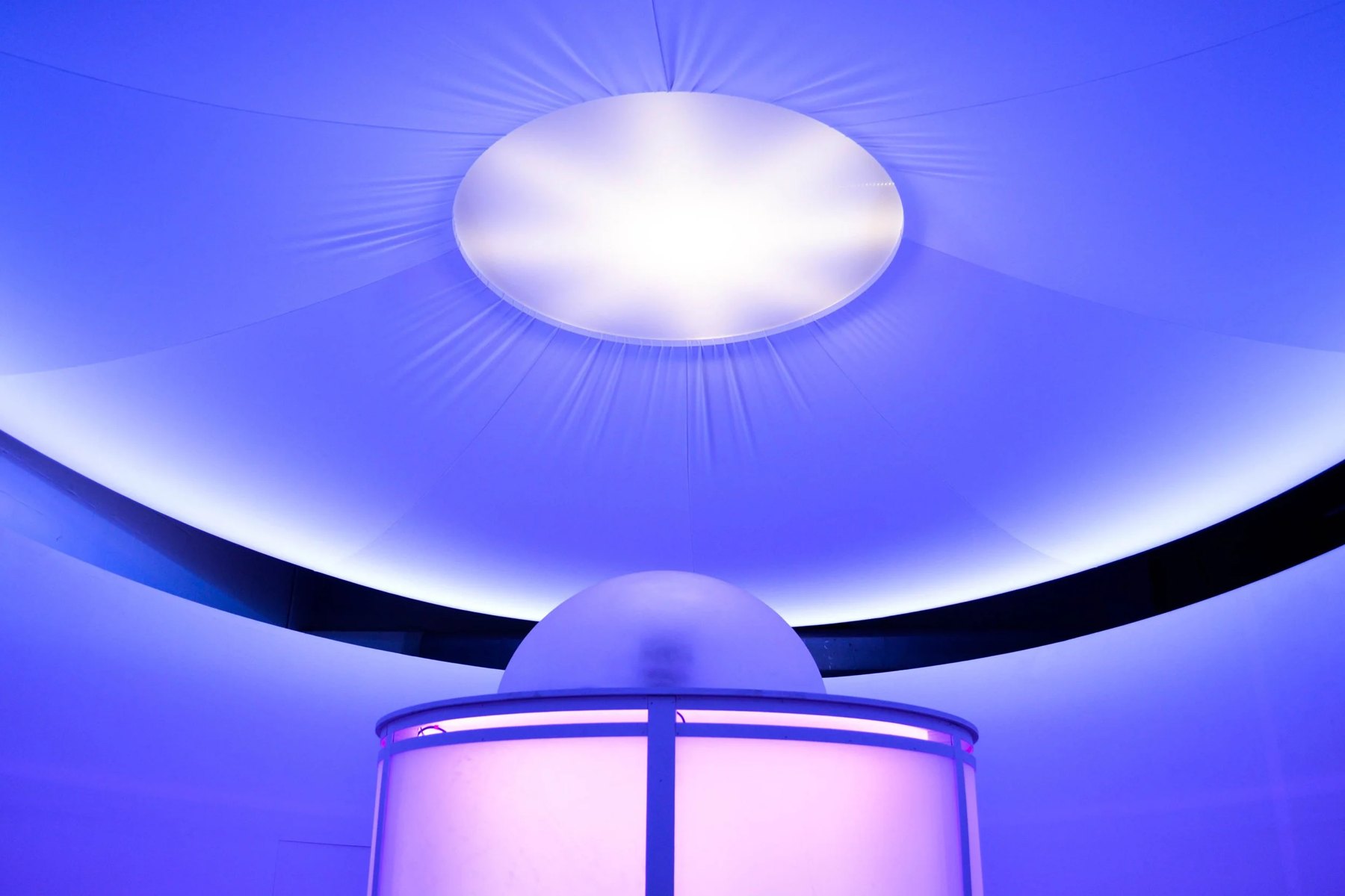 A white fabric canopy glowing blue above the top of the chamber.
