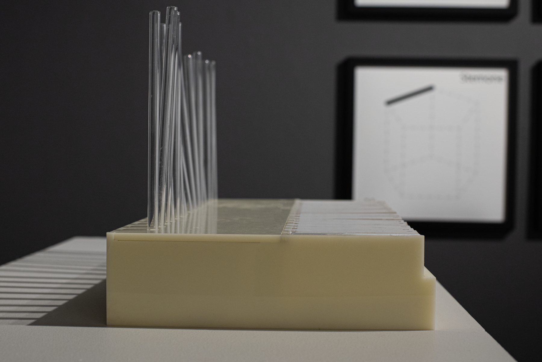 Side view of the Odor Organ: clear glass tubes rising from the instrument body, with a framed notation print behind.