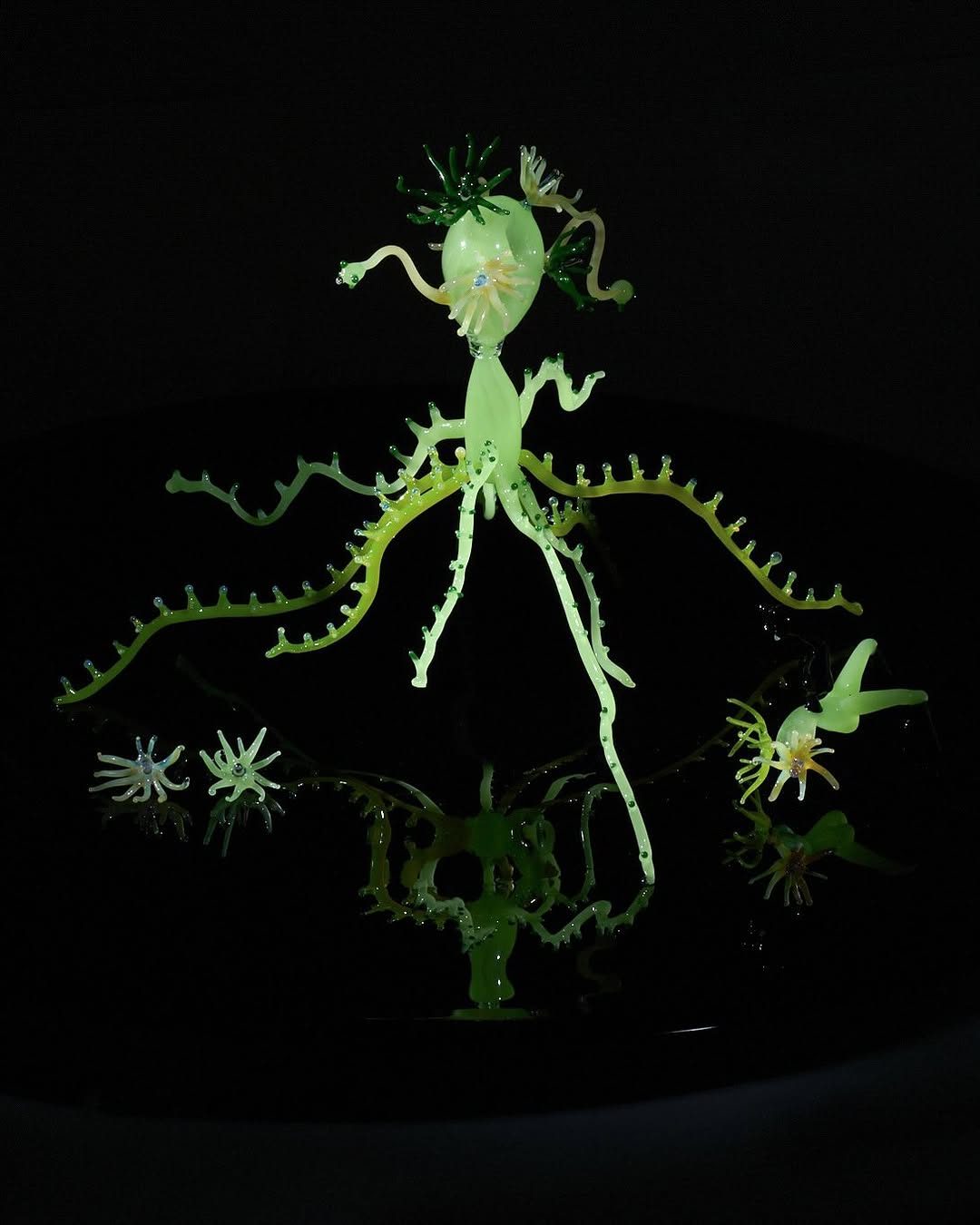 Green glass figure with tentacles on a black disc