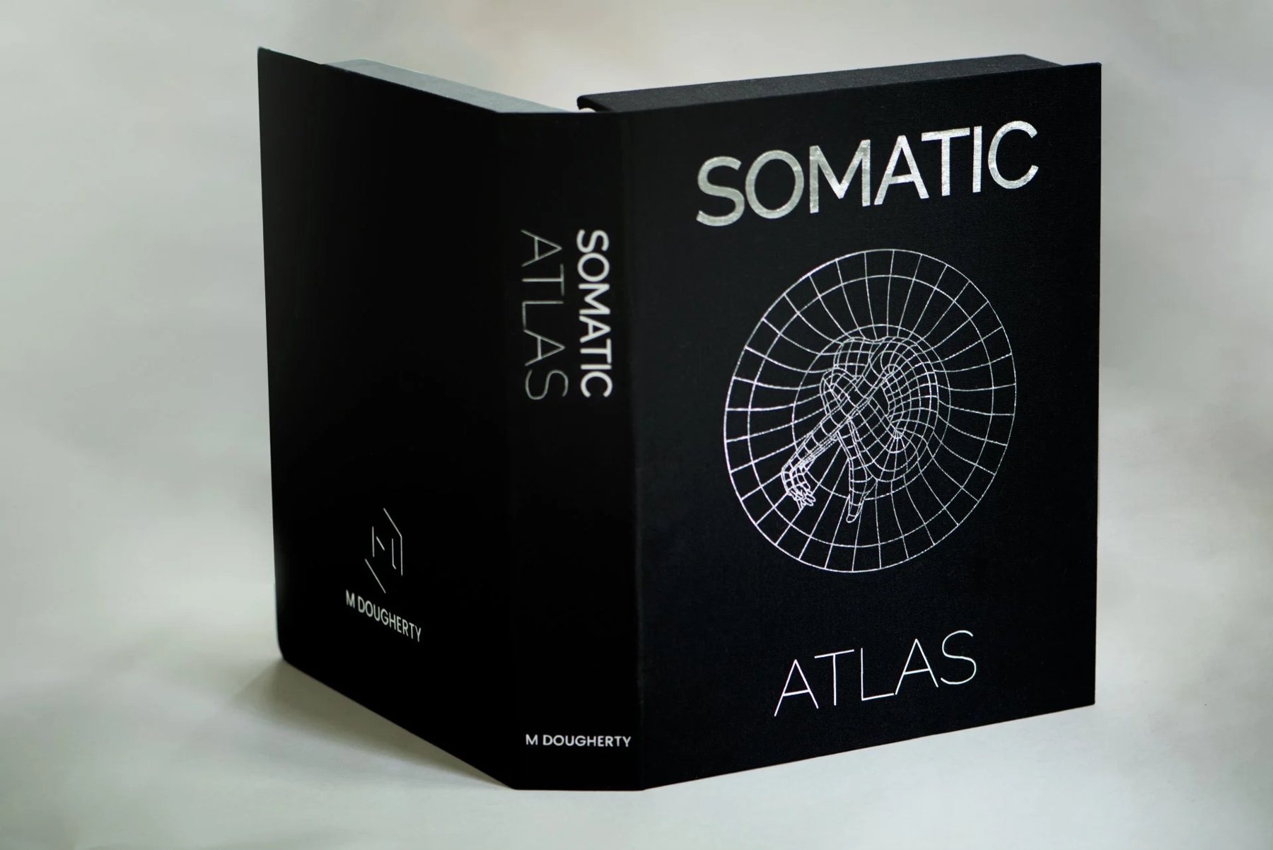 The Somatic Atlas box, black with a white line drawing of a body inside a radial grid.